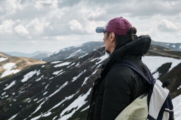 Hiker with backpack overlooking snow-covered mountain landscape