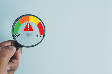 A concept of business risk management and assessment. A magnifying glass over a risk meter showing the level from low to high, a tool for project planning and strategic analysis.,copyspace.