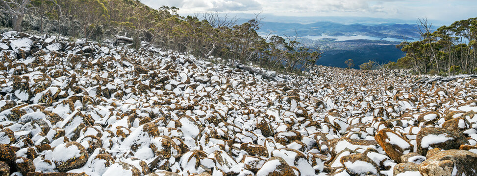 Panorama view of snow covering boulders in a rockfall in a mountain valley