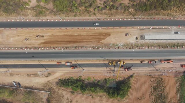 Drone footage aerial view scenic landscape Cranes and mechanics repair high-voltage power lines along a rural road under construction 
