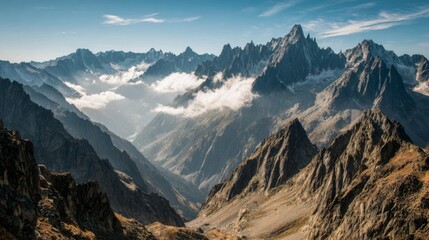 A wide shot of a high-altitude mountain range with sharp peaks and valleys, partially covered in clouds, creating a mystical and dramatic landscape