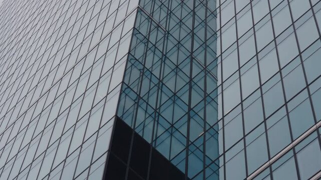 POV close-up shot from inside car driving through streets of modern city. Windshield view urban landscape, skyscrapers windows glass, lighting poles and communications in slow motion, cloudy day