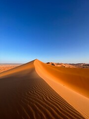 Golden sand dunes under clear blue sky in the Sahara desert