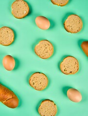 Fresh eggs and sliced bread on green background
