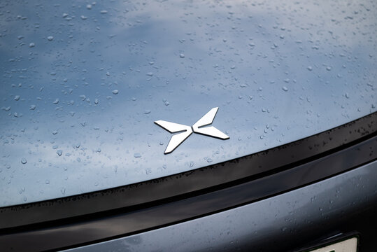 Kyiv, Ukraine - July 30, 2025:  Close-up of XPeng P7 electric car logo on wet hood after rain.