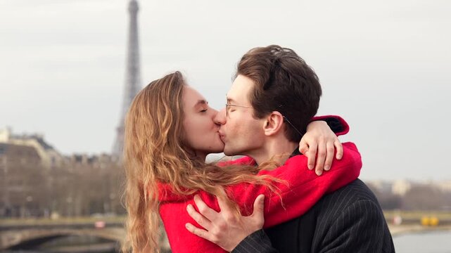 Loving couple sharing a romantic kiss with the Eiffel Tower in the background on a sunny day in Paris