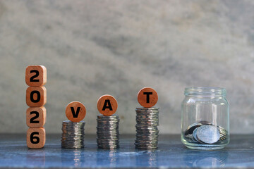 Coins stacked on each other forming the word vat with wooden cubes