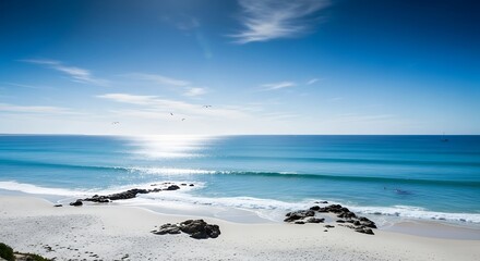 Fototapeta premium Serene Beach Landscape with Calm Blue Waters, Rocks, and Distant Horizon View