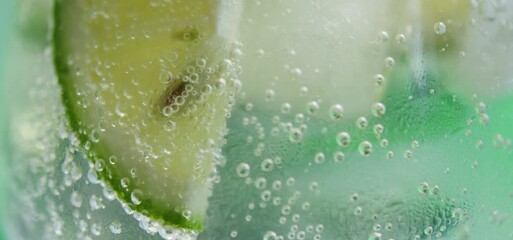 Ultra Slow Motion Lime Slice Bubbling in Sparkling Drink | 4K - Powered by Adobe