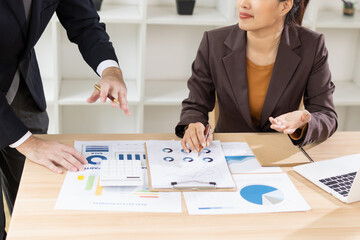 Two Asian business people with analyzing financial report working together in office.