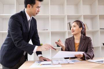 Two Asian business people with analyzing financial report working together in office.