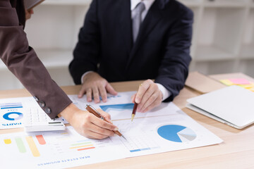 Asian businesswoman and businessman with paper documents financial analysis data charts in office working space.