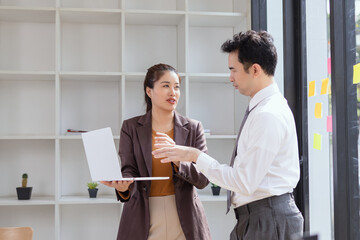 Asian businesswoman and woman talking on work with laptop standing in office.