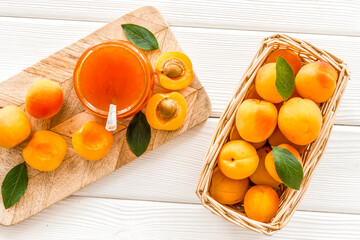 Friut background with apricot jam on white wooden background top view