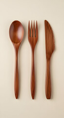 Polished wooden cutlery set: Spoon, fork, and serrated knife on a neutral background