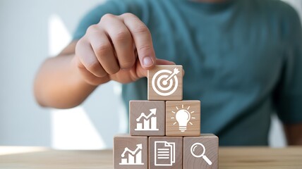 Hand stacking wooden blocks with business growth icons and target symbol strategy success