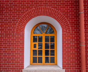 A window with a tree in the arch of a brick wall.