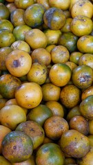 Close-up of local oranges with natural blemishes at a traditional fruit market, ready for sale.
