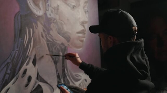 Artist Works on a Painting in the Studio Medium Panning Shot From Back