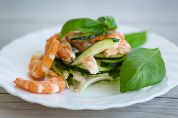 Original recipe for salad with shrimps and greens on a wooden table