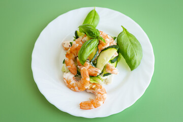 Shrimp salad with greens and cucumber slices on a green background