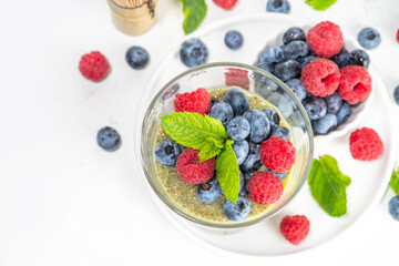 Healthy breakfast chia pudding with with matcha latte tea and fresh summer berries in glasses, white background copy space