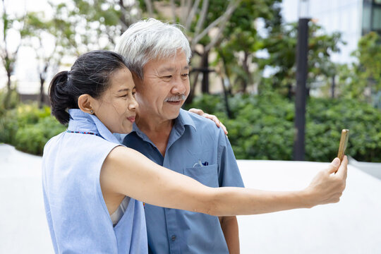 Modern Asian Senior Man taking selfie, capturing Precious Moments with His Wife Using a Smartphone