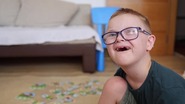 Portrait of a cute boy with Down syndrome smiling happily and mocking the camera. Authentic diverse people. Kid with disability. 