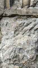 Close-up view of a weathered stone surface showcasing intricate textures and patterns. Sunlight accentuates the natural colors and features of the rock, creating a rustic aesthetic