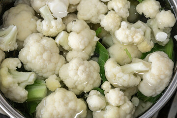 Fresh cauliflower is boiled in a saucepan with water. The vegetable is divided into florets and boiled in a saucepan.