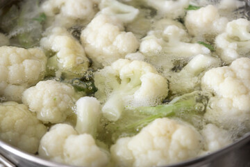 Fresh cauliflower is boiled in a saucepan with water. The vegetable is divided into florets and boiled in a saucepan.