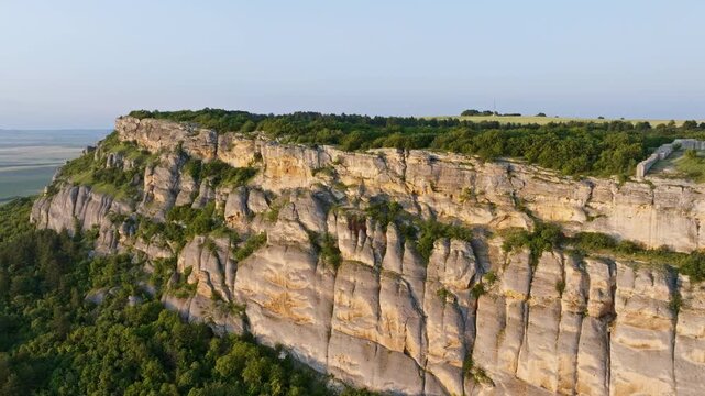 Historic limestone cliff Madara Rider carving, green summer fields and forest around, northeastern Bulgaria aerial, ancient relief from 8th century, heritage travel site, drone travel