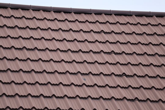 old roof tilesHouse roof with steel roofing sheet. Traditional metal shingle tiles. Gray modular tile effect roof panel. Profiled metallic corrugated pantile as concrete slate. Building's cover