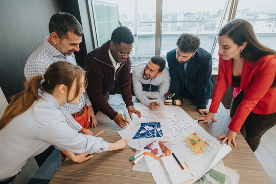 A group of professionals are actively working together on architectural plans in a contemporary office environment, emphasizing teamwork and innovation.