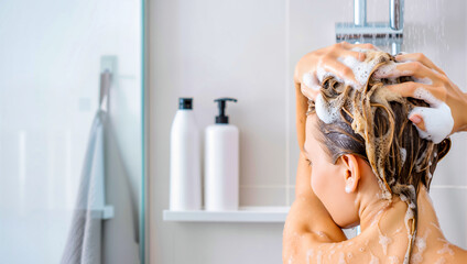 A blonde woman is washing her hair with shampoo in the shower. A daily beauty routine for healthy hair and professional hair care treatment.