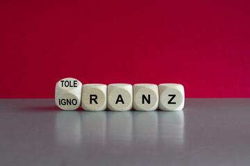 Ignorance or tolerance? Turned dice and changes the German word Ignoranz (ignorance) to Toleranz (tolerance). Beautiful pink background.