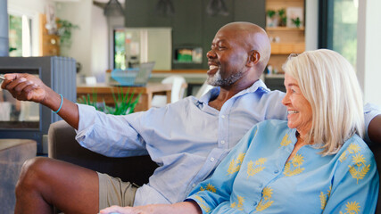 Multi-Racial Senior Couple On Sofa At Home Together Watching TV