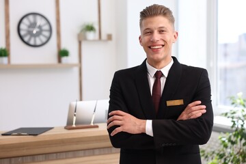 Portrait of smiling receptionist with crossed arms in hotel