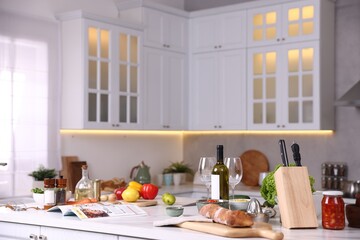 Different products and bottle of wine on counter in stylish kitchen