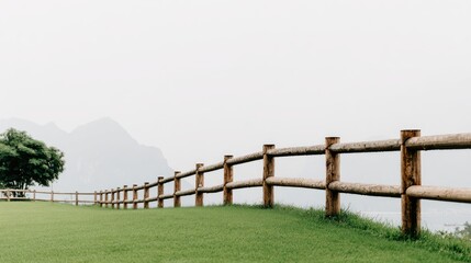 Fototapeta premium Wooden fence line against a misty mountain backdrop.