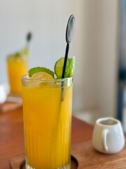 A glass of fresh orange juice with lime and mint on it. Juice on a wooden table in a cafe