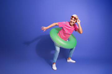 Excited elderly woman wearing striped shirt and green swim ring ready for summer fun on vibrant...