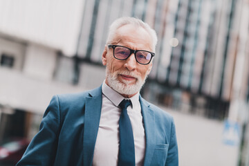 Smiling businessman in a stylish suit standing outdoors in a modern cityscape environment with...