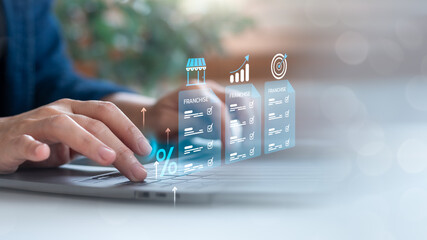 Hands typing on a laptop with holographic franchise documents, growth chart, and target icon....