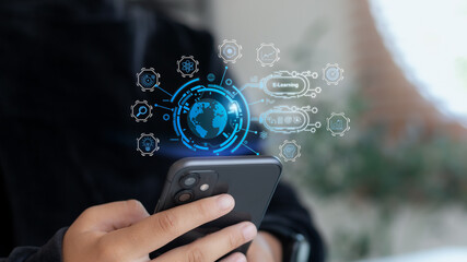 Close-up hand using smartphone with holographic E-learning icons and global education interface. Concept of online learning, digital knowledge, and remote education.