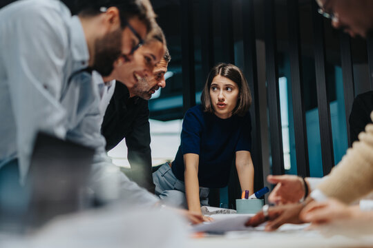 A group of diverse business colleagues brainstorming ideas in a modern office setting, emphasizing teamwork and innovative thinking. The team includes members of different ages and cultural