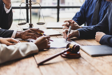 Lawyers discussing contract with gavel on table, legal proceedings and negotiations.