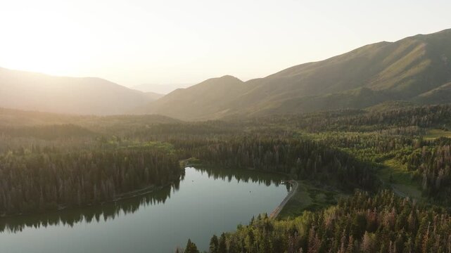 Aerial view of Payson Lake surrounded by verdant forests and majestic mountains bathed in the warm glow of the setting sun, Payson, Utah, United States.