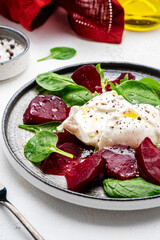 Gourmet salad with burrata cheese, baked beets, spinach and olive oil, white background, top view