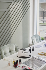 Modern manicure table displaying professional nail dryer lamp, various nail polish bottles,...